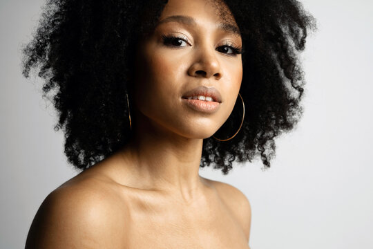 Portrait of a female model of Afro appearance. Black hair is curly. Photo shoot in a photo studio on a white background. copy space. Beautiful smooth facial skin.