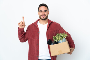 Young caucasian man making a move while picking up a box full of things isolated on white...
