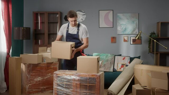 Repairman worker is preparing build furniture in apartment, placing boxes and equipment. Handyman at work. Housebuilder do maintenance in room, moving to new flat or office. Daylight
