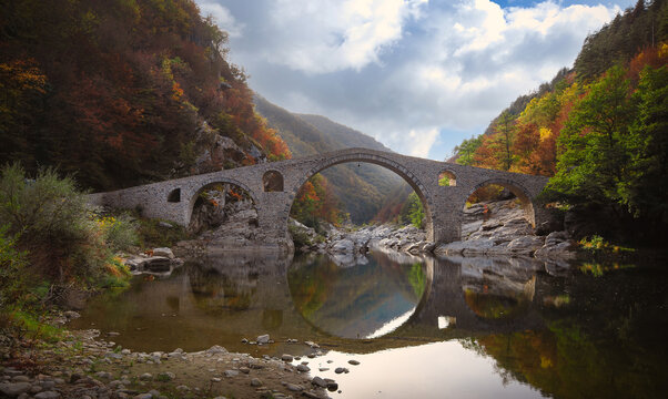 Ancient stone bridge called Devil's bridge in autumn forest. Ottoman Architecture near  the town of Ardino , Rhodope Mountains and Arda river, Kardzhali Region, Bulgaria. 