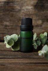 Eucalyptus essential oil and fresh eucalyptus leaves on wood background. © imagehub