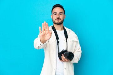 Young photographer man isolated on blue background making stop gesture