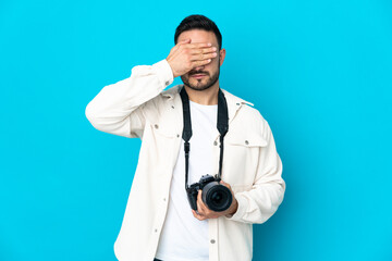 Young photographer man isolated on blue background covering eyes by hands. Do not want to see something