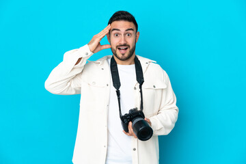 Young photographer man isolated on blue background with surprise expression