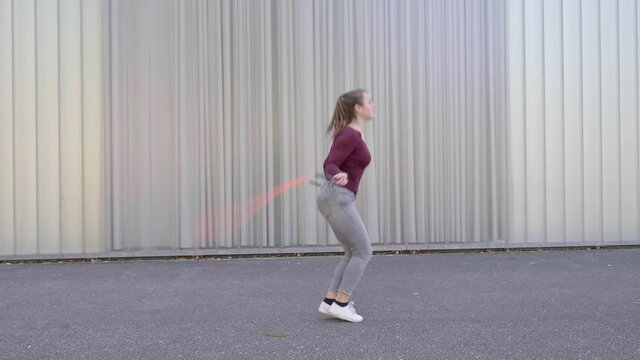 Young woman skipping rope and cartwheeling in the street