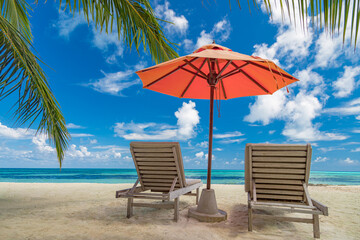 Beautiful tropical island scenery, two sun beds, loungers, umbrella under palm tree. White sand, sea view with horizon, idyllic blue sky, calmness and relaxation. Inspirational beach resort hotel