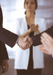 Unknown businesspeople are shaking their hands after signing a contract at meeting, close-up. Business communication concept