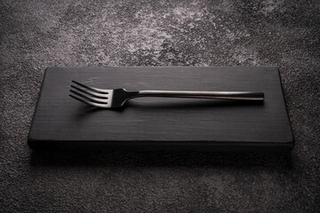 a black table fork on a wooden podium. stylish minimalistic still life