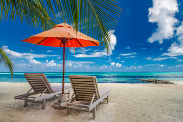 Beautiful tropical island scenery, two sun beds, loungers, umbrella under palm tree. White sand, sea view with horizon, idyllic blue sky, calmness and relaxation. Inspirational beach resort hotel