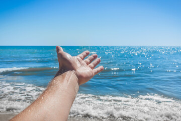 The young man stretched his hand forward to the sea and sky on the beach. The concept of freedom and rest at sea