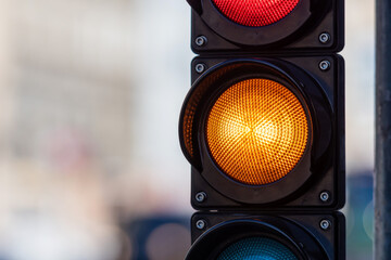 close-up of traffic semaphore with orange light on defocused city street background with copy space