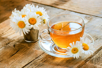 chamomile tea on wooden background, transparent cup with warm aromatic drink, relaxation and detox