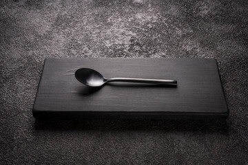 a black table little tea Spoon on a wooden podium. stylish minimalistic still life