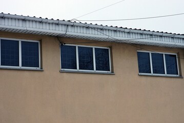 a row of three small windows on a brown concrete wall of a building under a white roof