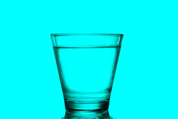A glass of water close up with pastel background