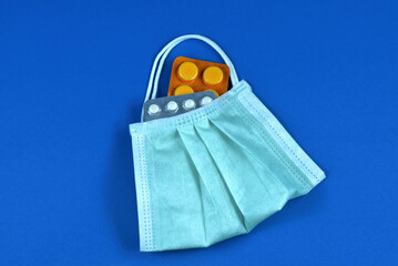 Face mask in the form of a bag with antibiotic pills on a blue background. Home delivery from a pharmacy during the influenza and coronavirus pandemic.