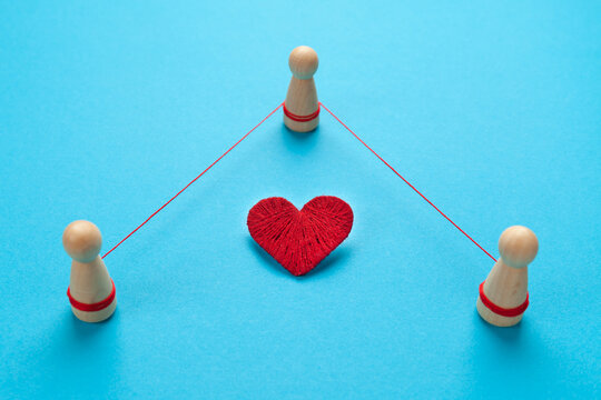 Three people in a love story. Betrayal and treason in the family, concept. Figures of people are tied with a thread on a blue background.