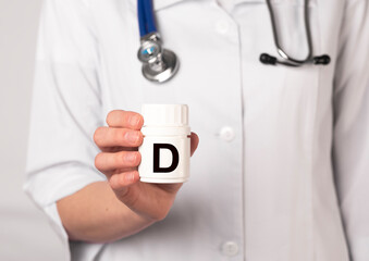 Female doctor or pharmacist in white coat holding jar of D vitamin