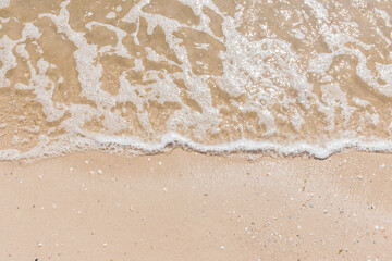 Fototapeta na wymiar Blue sea water on light yellow beach sand