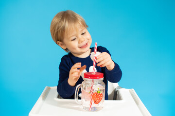 Baby boy holding a glass against a blue background