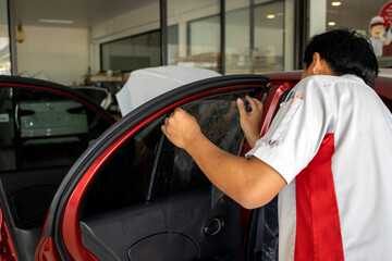 master installs a tint film for the car glass with soft-focus and over light in the background....