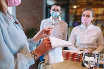 The waiters of the restaurant in a medical mask learns to distinguish between the glasses.