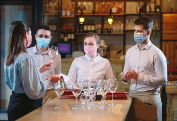 The waiters of the restaurant in a medical mask learns to distinguish between the glasses.