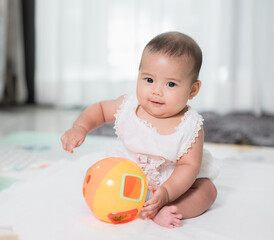 Asian baby cute in the living room at home playing ball toy with family.