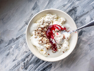 Light protein breakfast, rustic cottage cheese with cream and seeds, with raspberry jam in a deep plate close-up