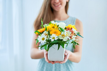 Woman holds decorative colorful bright fresh flower hat box at spring time