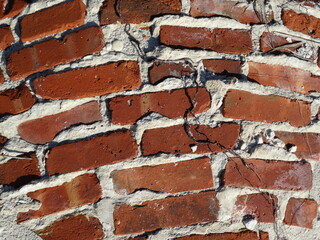 Old curved red brick wall with cracks