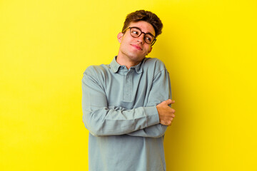 Young caucasian man isolated on yellow background hugs, smiling carefree and happy.