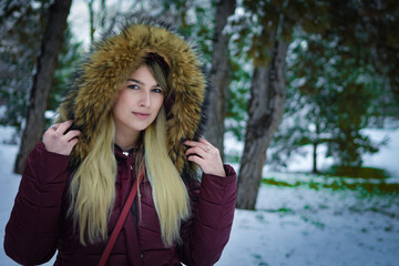 Beautiful blonde girl walking in the park on snowy winters day.