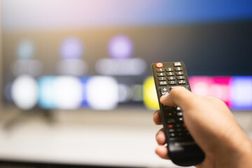 Close up male hand holding remote control pointing to change the programme television.