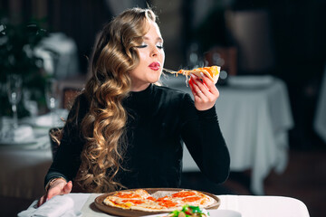 Young beautiful girl alone eating pizza in a restaurant.