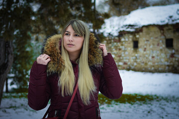 Naklejka premium Beautiful blonde girl walking in the park on snowy winters day.
