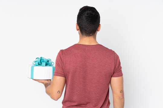 Pastry chef with a big cake isolated on white background in back position
