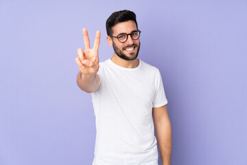 Naklejka premium Caucasian handsome man over isolated background smiling and showing victory sign