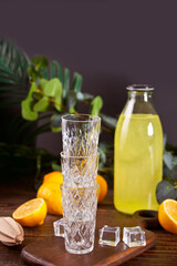 Italian drink lemon liqueur limoncello in a bottle and empty glasses on the wooden table