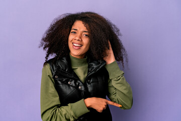 Young african american curly woman isolated on purple background trying to listening a gossip.