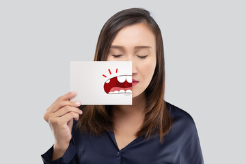 Asian woman in the dark blue shirt holding a paper with the broken tooth cartoon picture of his...