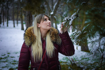 Beautiful blonde girl walking in the park on snowy winters day.