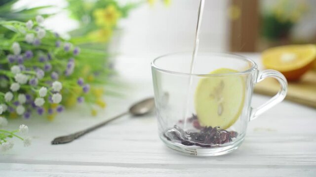 Tea is poured into a glass transparent cup on a wooden table