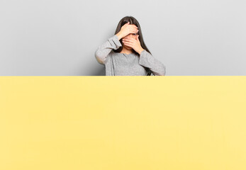 young pretty woman covering face with both hands saying no to the camera! refusing pictures or...