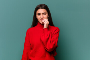 Young Indian woman isolated on blue background biting fingernails, nervous and very anxious.