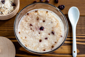 top view of bowl of oatmeal on wooden background closeup, rustic design, healthy nutrition, fast breakfast of instant porridge with freeze-dried berries