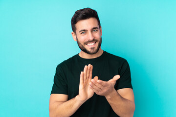 Caucasian handsome man isolated on blue background applauding after presentation in a conference