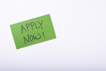 Apply Now word written on a Green color sticky note with a White background.