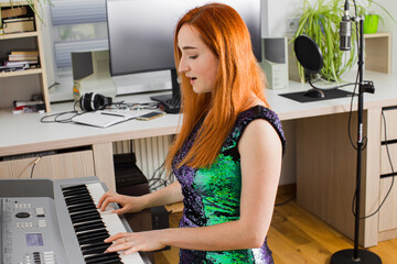 The young woman is playing in the studio on a synthesizer