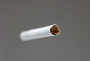 Single white unlit cigarette close up macro studio shot isolated on gray background shallow depth of field